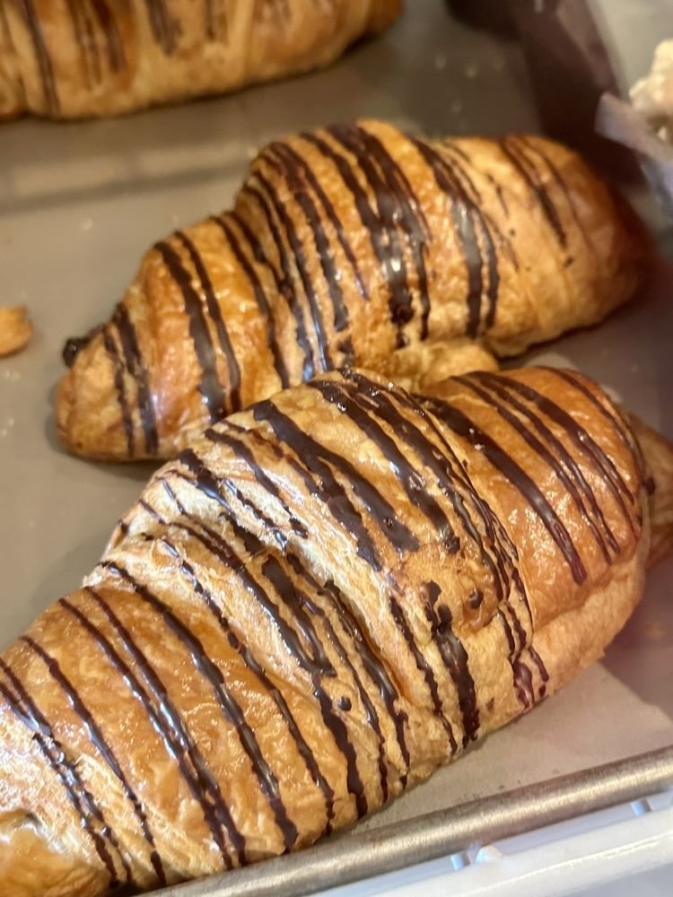 Chocolate-drizzled croissants on a baking tray