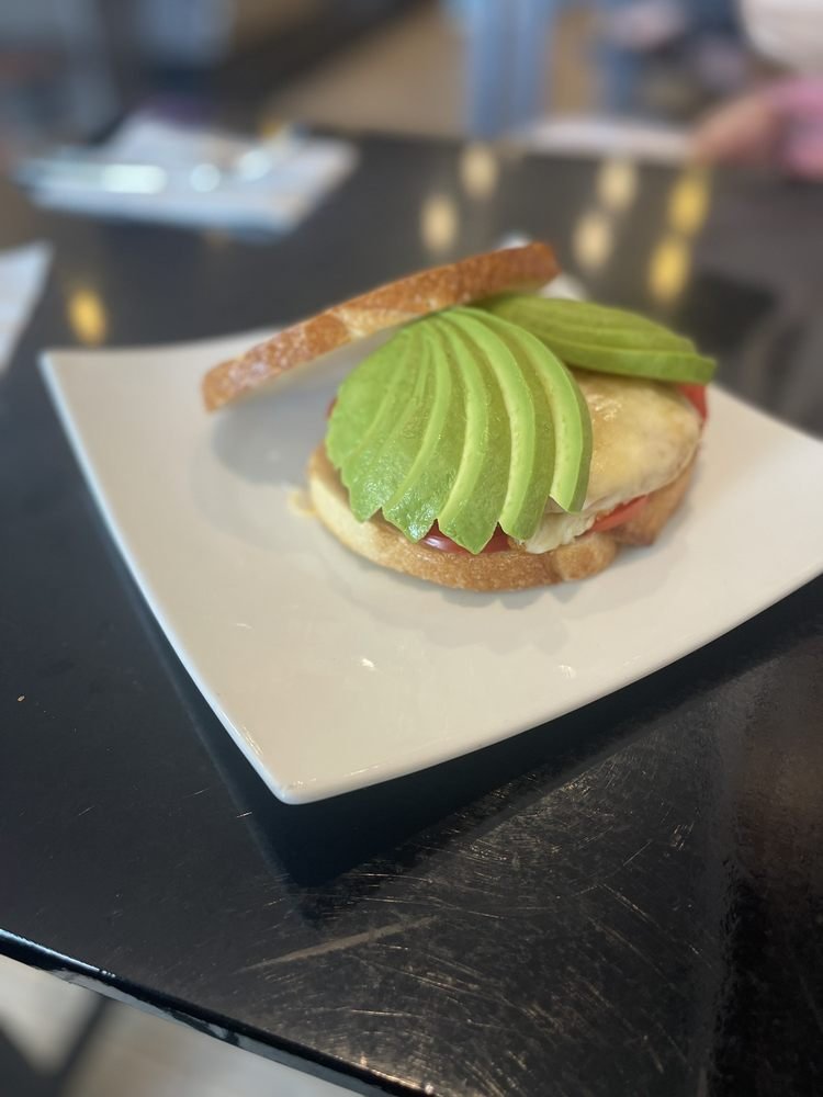 Open avocado, egg and tomato sandwich on a white plate